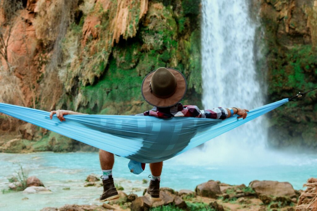 Voyageur détendu dans un hamac face à une cascade, symbole du voyage sur mesure SéMa